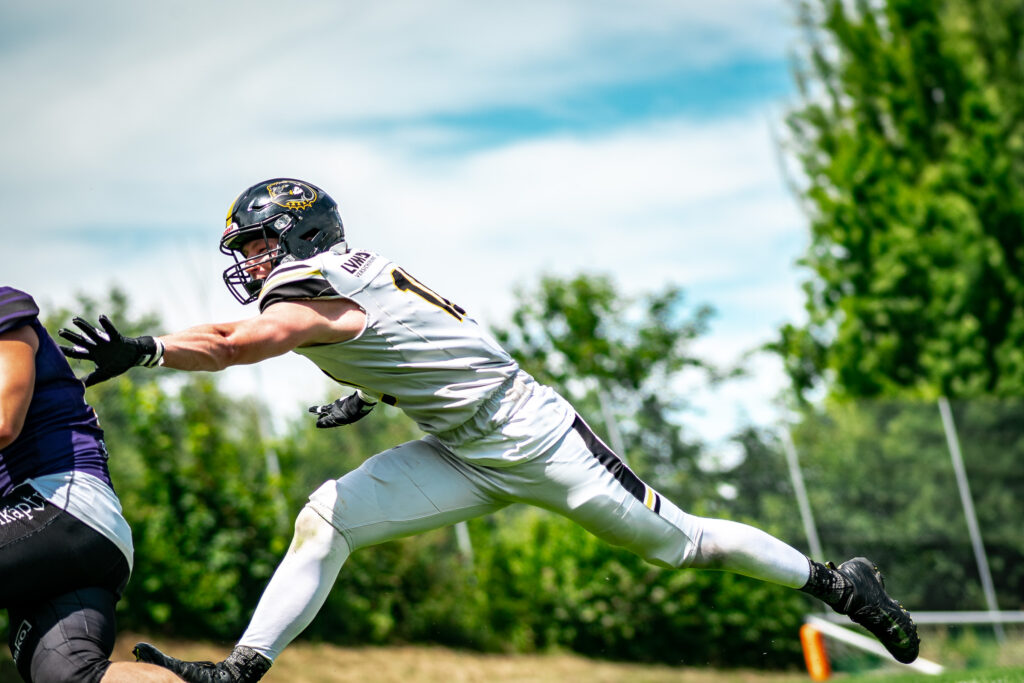 Football-Spieler streckt sich im Sprung nach dem Ball