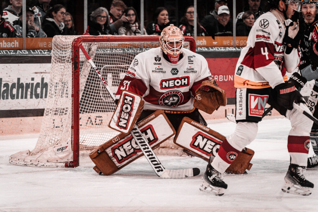 Eishockey-Torwart im rot-weißen Trikot vor dem Tor
