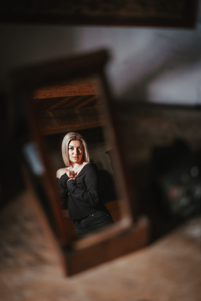 Frau in dunkler Kleidung, durch einen unscharfen Holzrahmen fotografiert