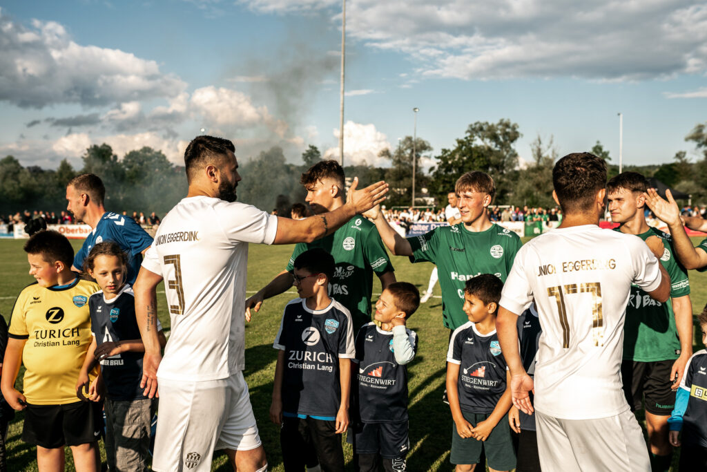 Spieler in hellen und dunklen Trikots stehen in einer Gruppe am Spielfeldrand