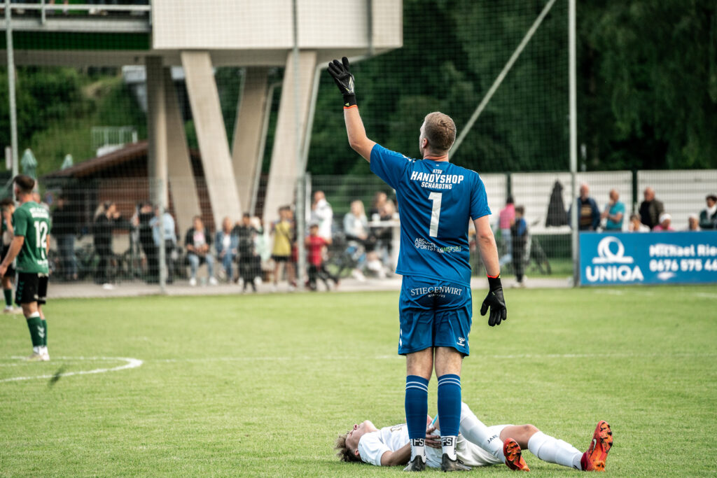 Torwart in blauem Trikot im Strafraum bei einem Fußballspiel
