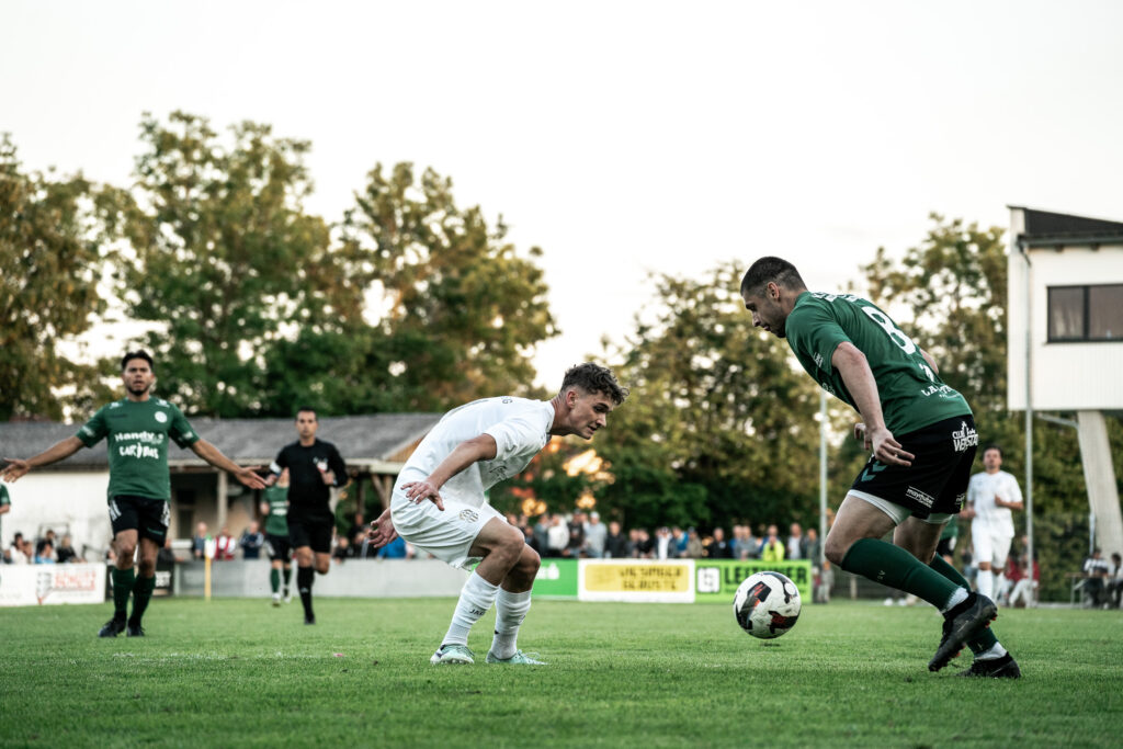 Zweikampf zwischen Fußballspielern in grünen und weißen Trikots