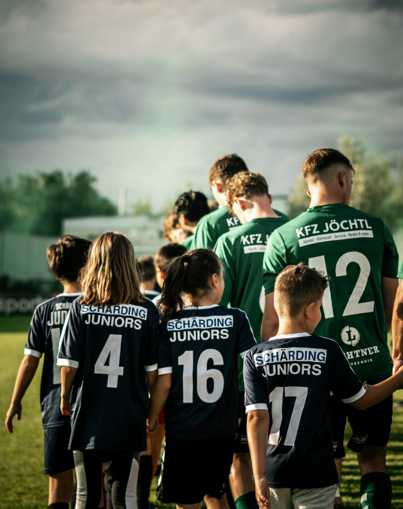 Spieler von hinten mit Rückennummern beim Einlaufen auf das Spielfeld