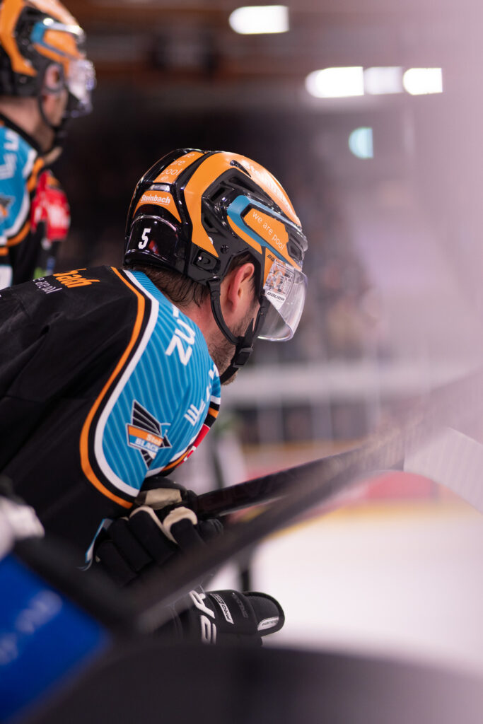 Eishockeyspieler mit Helm in blau-orangem Trikot