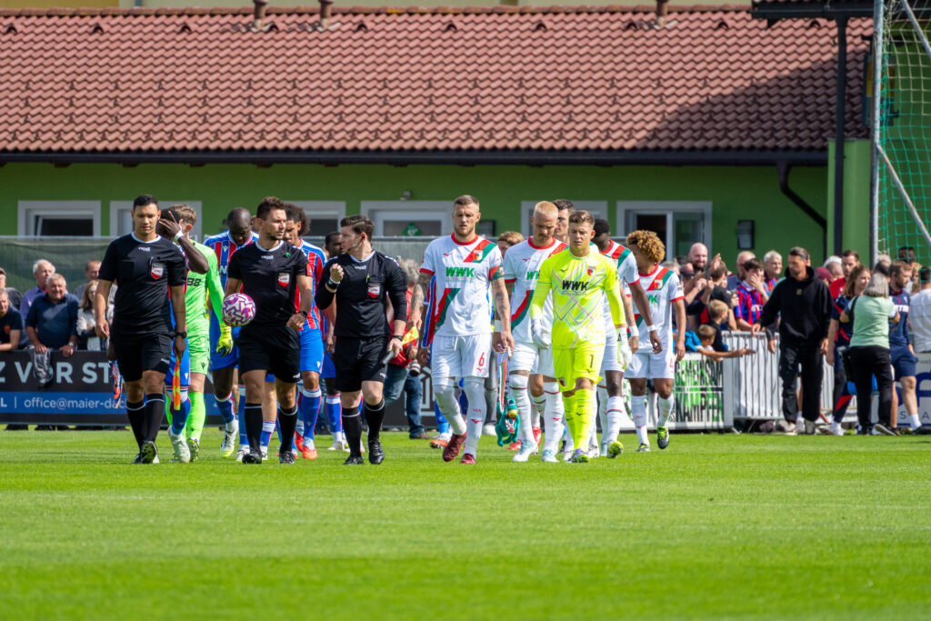 Spieler gehen auf einem Fußballplatz zu ihren Positionen