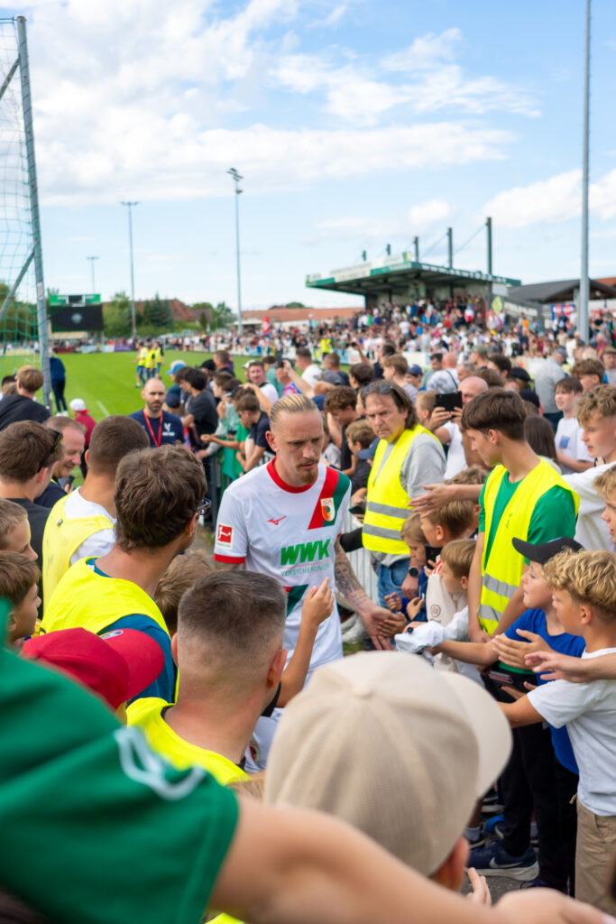Zuschauer in bunter Kleidung am Spielfeldrand
